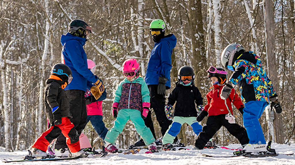 Six young children with two snowsports instructors during a ski lesson.
